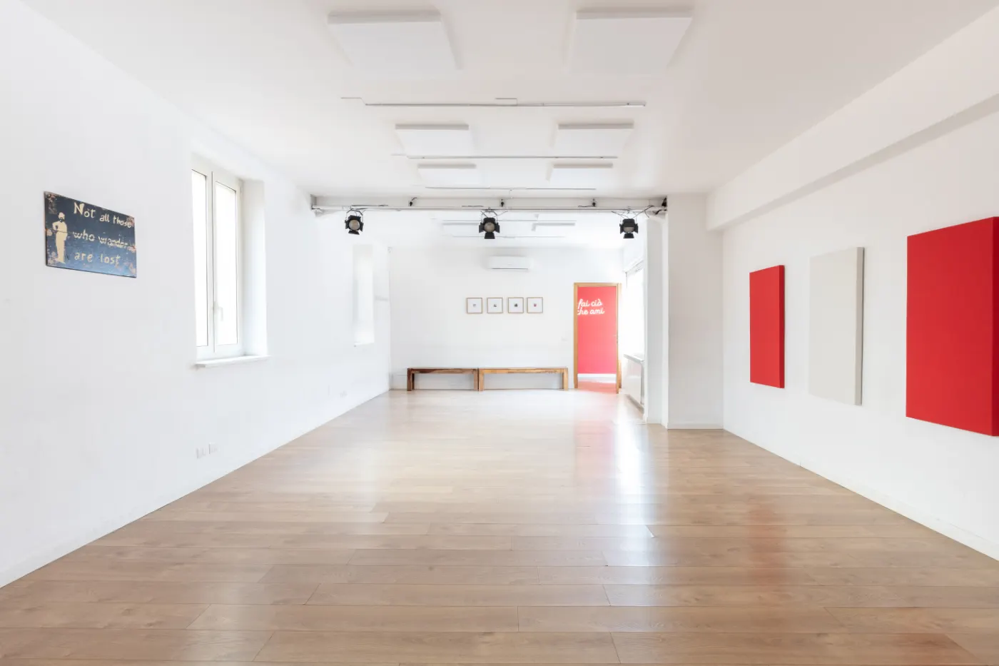 Una sala vuota con il parquet e i pannelli rossi alle pareti, pronta per le prove